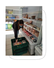 photo montrant une bénévole entrain de faire la mise en rayon dans le frigo